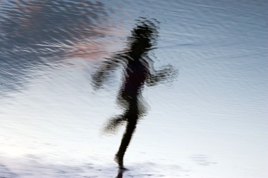 A blurred image of a person running at the beach.