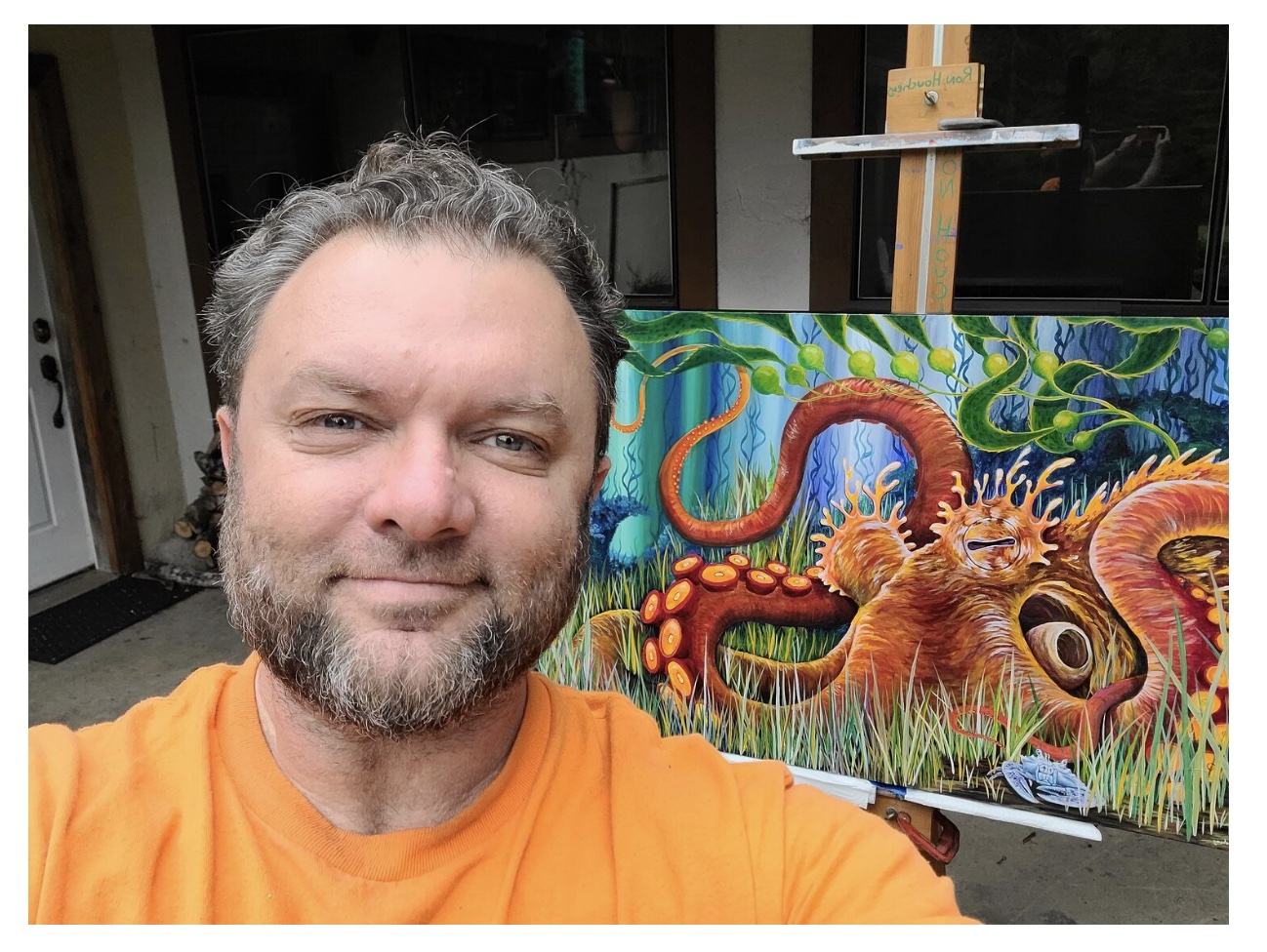 A man with short curly grayish hair. He is standing in front of a. mural showing a big octopus.
