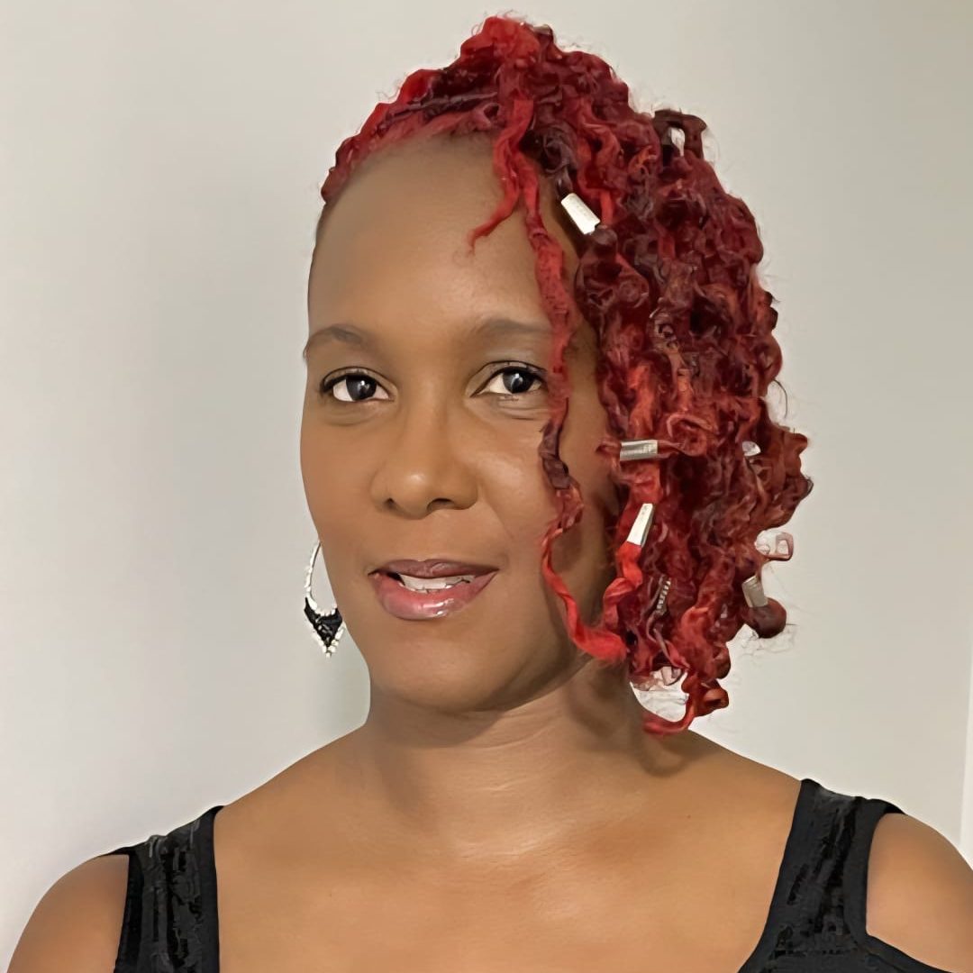 A black woman with red curly hair, wearing a black top.