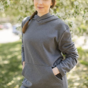 A female presenting person with dark hair in a braid wearing a dark gray hoodie.