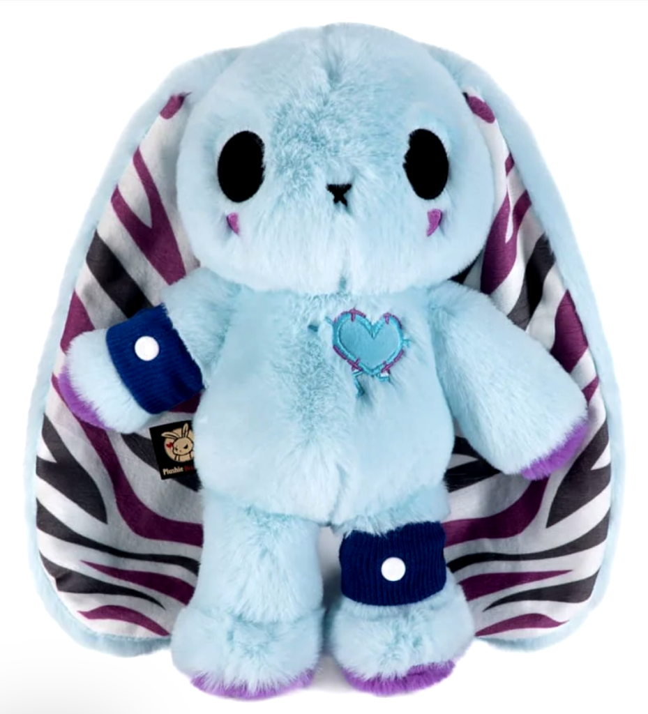 A light blue rabbit plushie with long ears that are purple, white, and black zebra striped. The bunny has black braces on its left knee and right arm as well as two purple spots under its eyes to represents the fatigue that comes with EDS. 