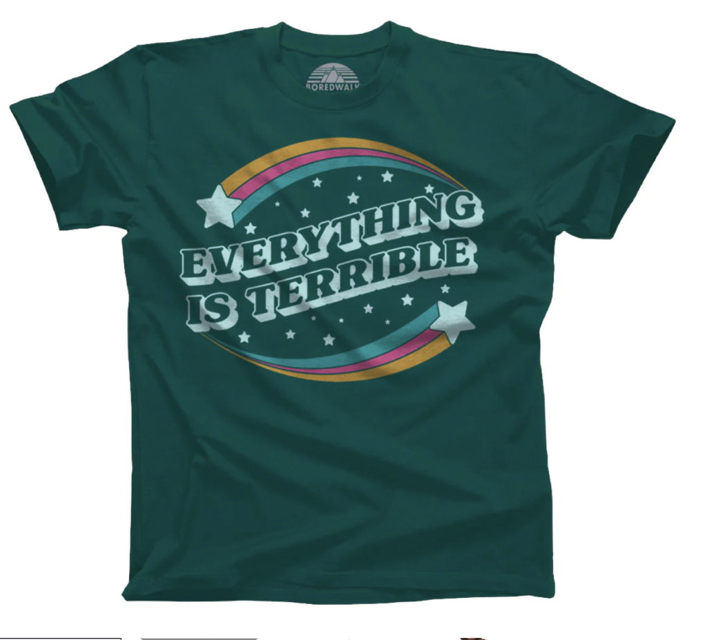 A dark green t-shirt with the words "Everything Is Terrible" written on it with shooting stars with rainbow tails surrounding the words. 