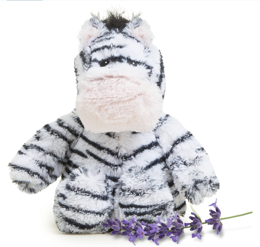 A small, plush zebra with a large muzzle sits upright with its hind legs out front. It is fuzzy with black and white strips. 