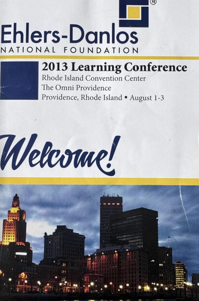 Cover of the Ehlers-Danlos National Foundation 2013 Learning Conference welcome brochure. The cover reads "2013 Learning Conference" and lists the Rhode Island Convention Center and The Omni Providence in Providence, Rhode Island, with conference dates of August 1–3. A nighttime photograph of the Providence skyline appears at the bottom of the cover.