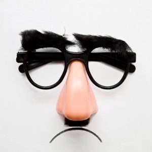 Novelty disguise glasses with bushy eyebrows, a large plastic nose, a small mustache, and a drawn frown on a white background.