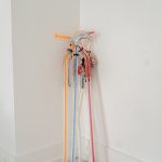 Four colorful walking canes decorated with charms lean together in a corner, used as mobility aids for someone with Ehlers-Danlos syndrome (EDS).