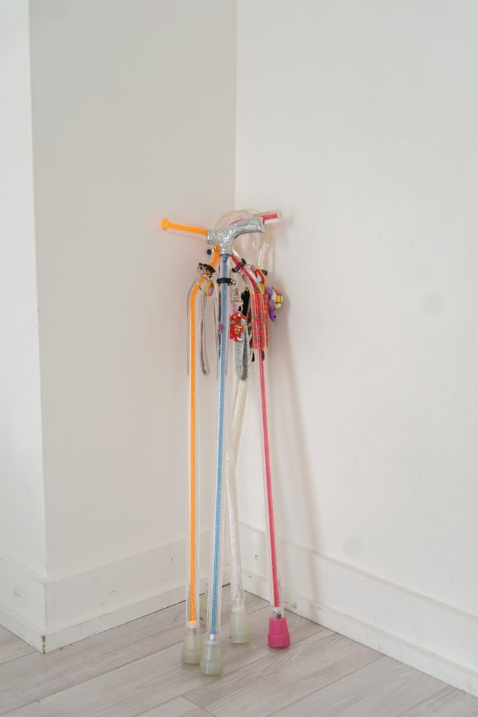 Four colorful walking canes decorated with charms lean together in a corner, used as mobility aids for someone with Ehlers-Danlos syndrome (EDS).